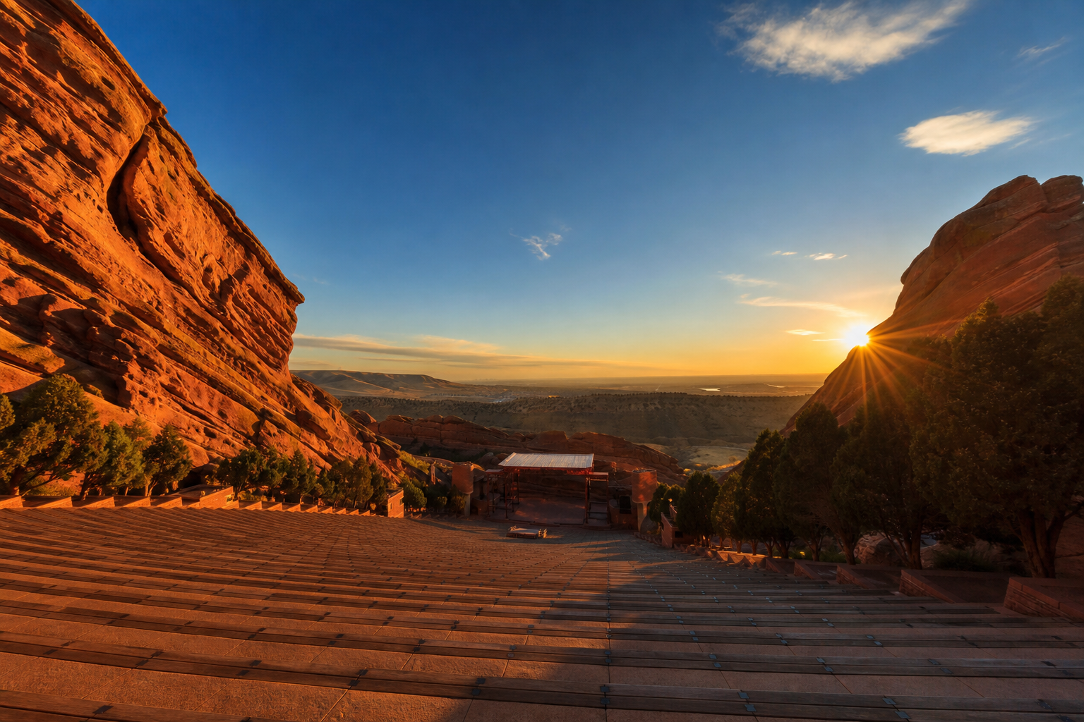 Red Rocks Amphitheatre at golden hour — massive red sandstone formations towering against a dramatic Colorado sky
